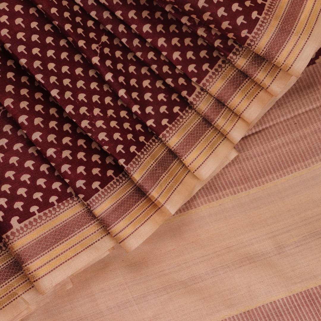 Close-up of maroon Tussar silk saree fabric, showing natural slub texture and printed pattern.