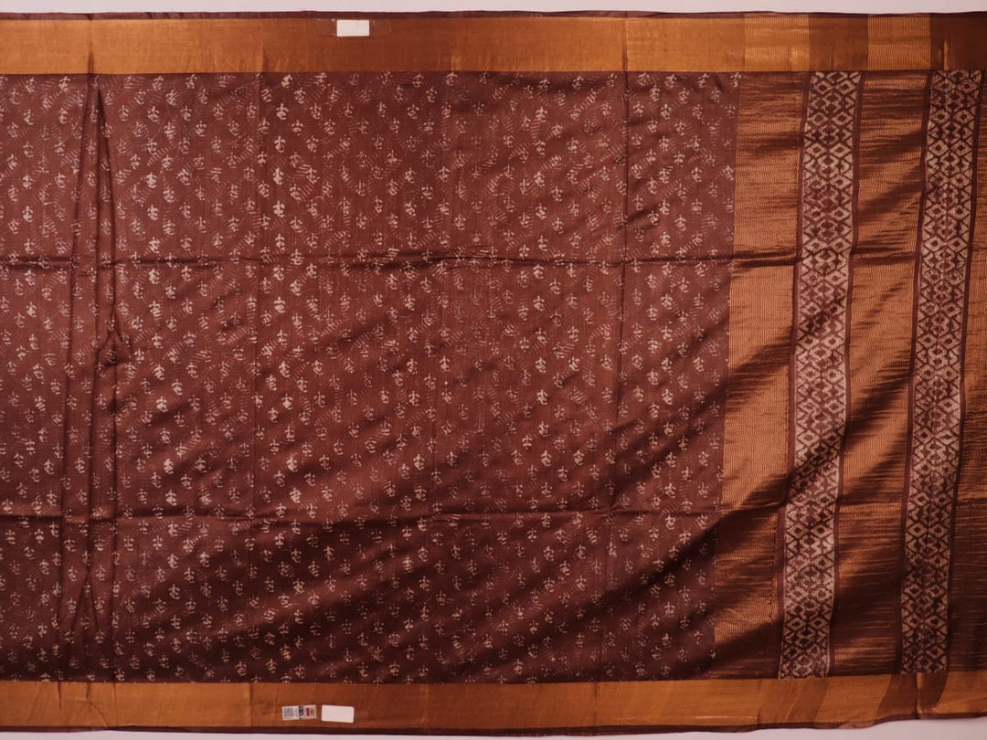 Close-up of the brown Tussar silk saree fabric, highlighting its natural slub texture and printed pattern.