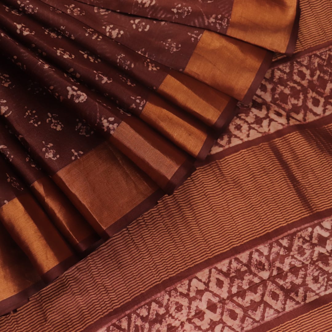 Close-up of the brown Tussar silk saree fabric, highlighting its natural slub texture and printed pattern.