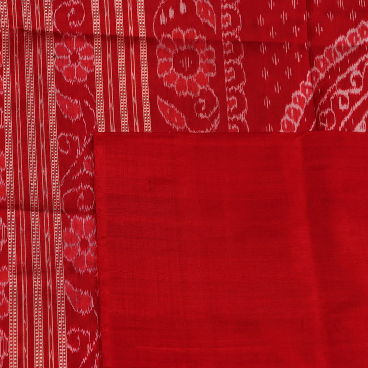 Close-up of green Sambalpuri silk saree fabric showing intricate woven motif texture and red thread details.