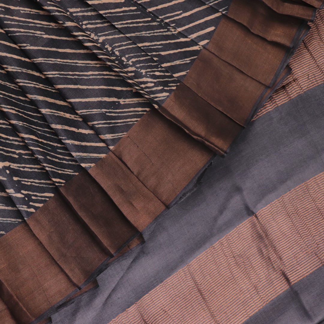 Close-up of the natural slub texture of grey printed Tussar silk saree fabric.