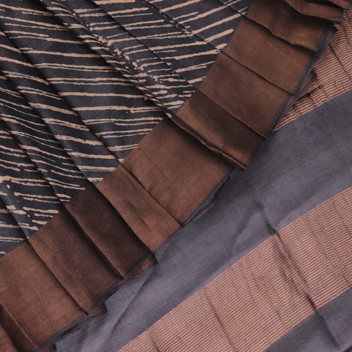 Close-up of the natural slub texture of grey printed Tussar silk saree fabric.