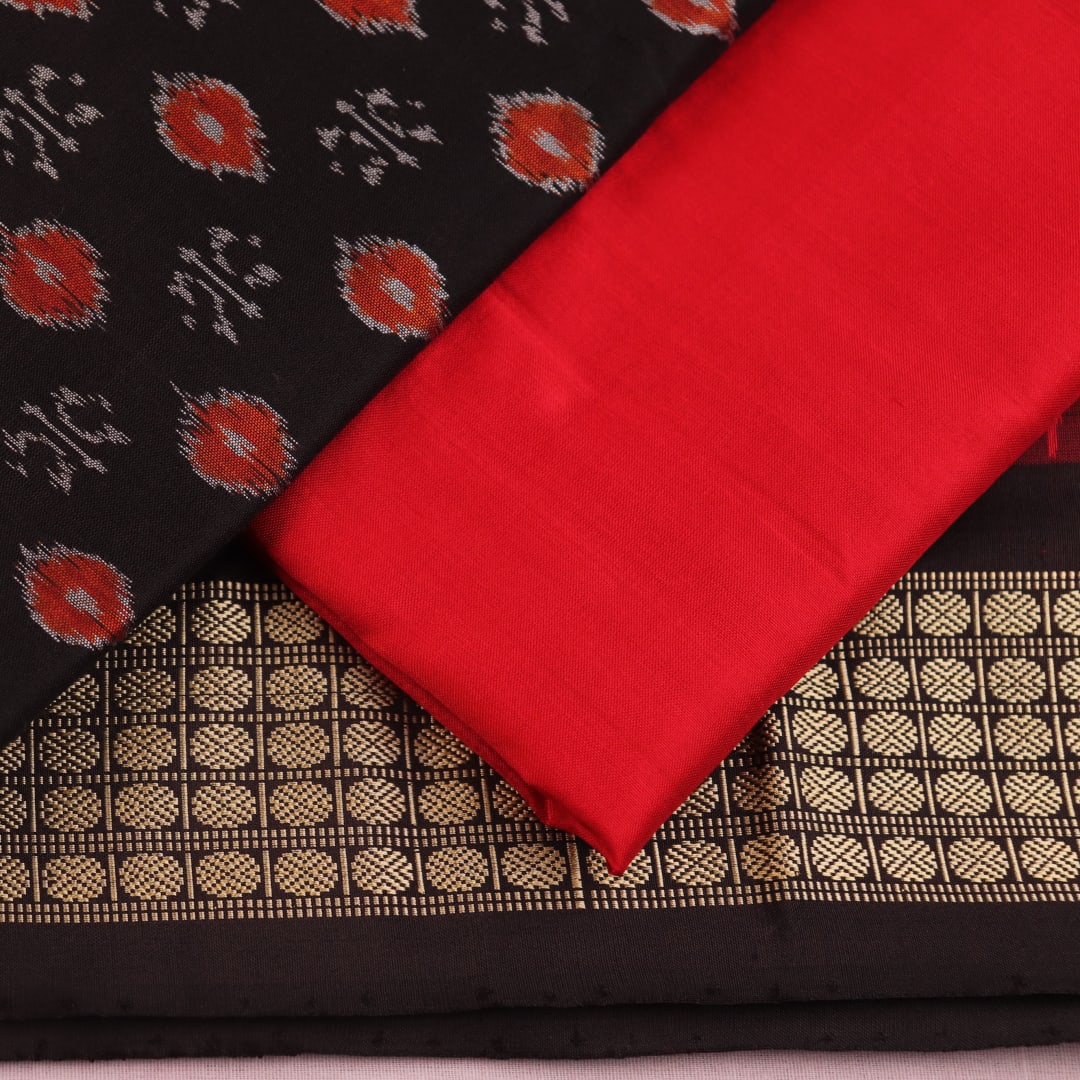 Detail of black Sambalpuri silk blouse piece from dress material, featuring red motifs.