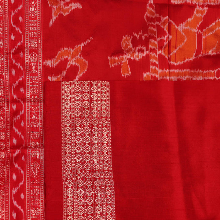 Close-up of a peach and red Sambalpuri silk saree fabric showing the intricate handloom texture and motifs.