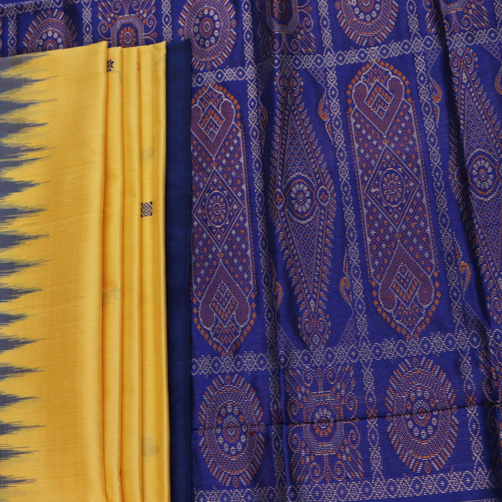 Textured close-up of yellow Bomkai silk saree fabric with blue butta pattern.