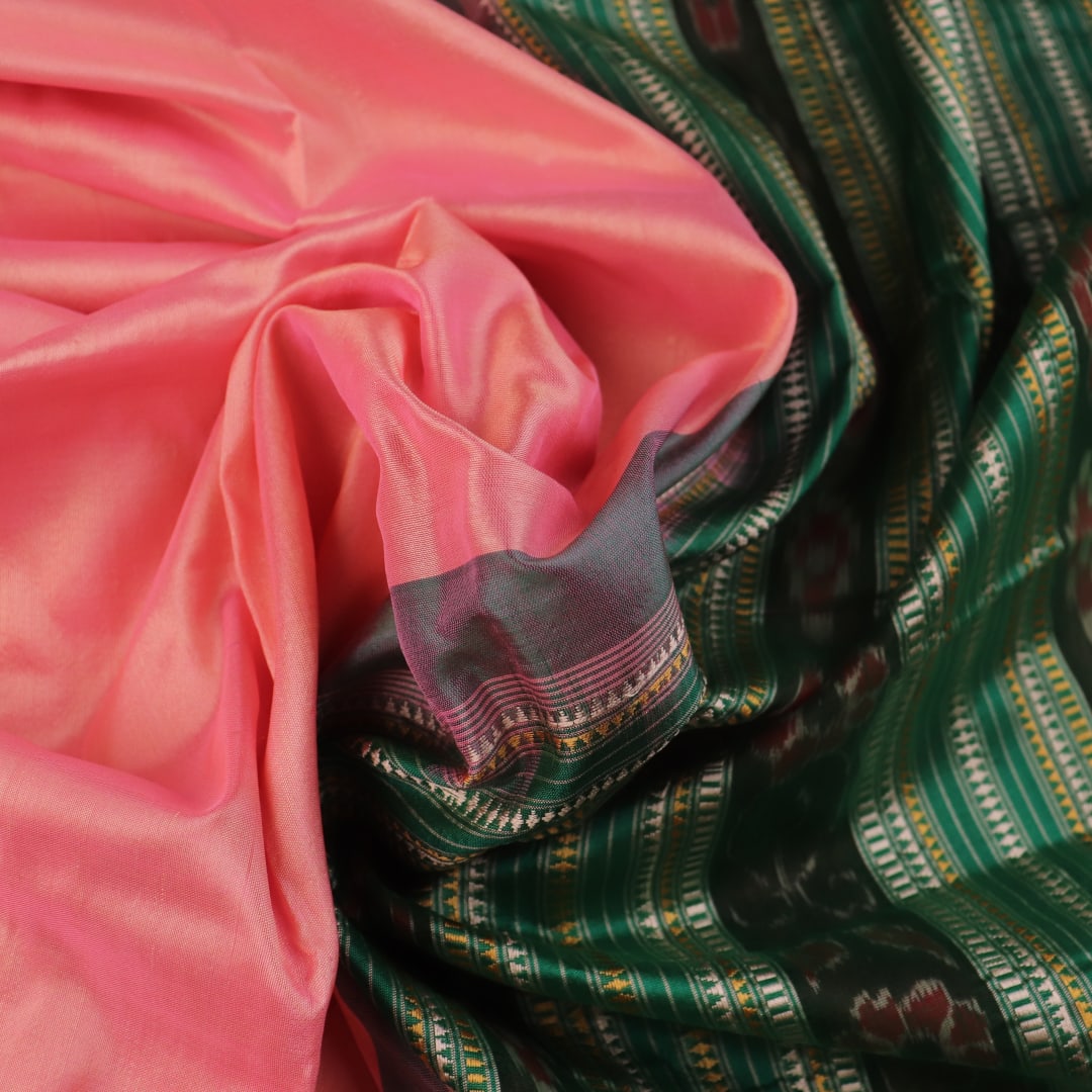 Close-up of the plain woven silk texture of a pink and green Sambalpuri saree.