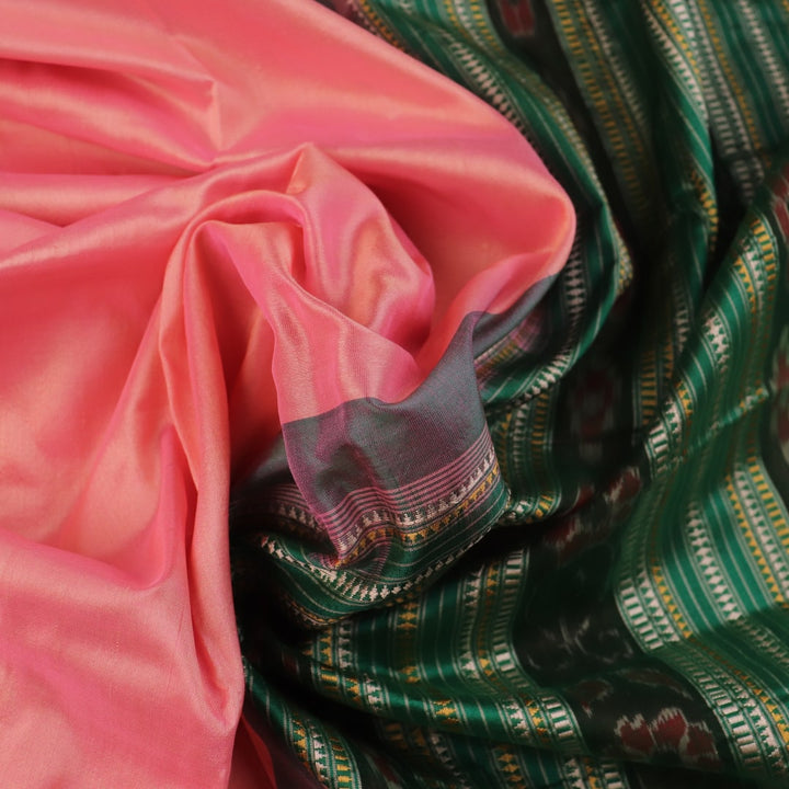 Close-up of the plain woven silk texture of a pink and green Sambalpuri saree.