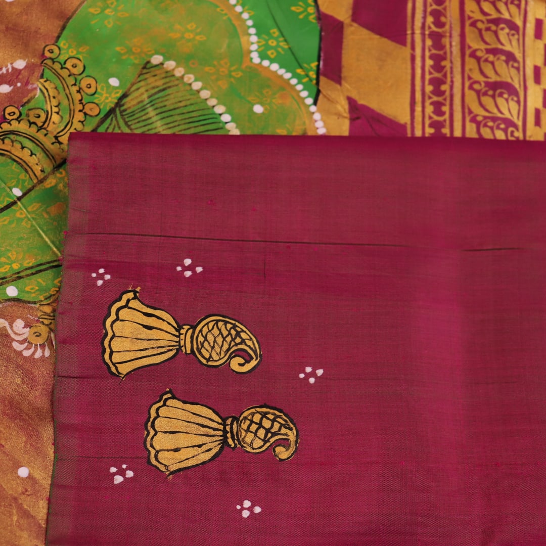 Close-up of magenta Patachitra silk saree fabric texture showing handloom weave and paint details.