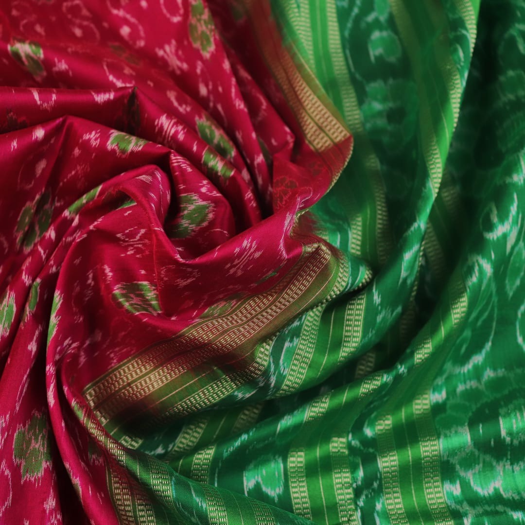 Close-up of magenta Sambalpuri silk saree fabric texture, showcasing intricate handloom weave and subtle motifs.