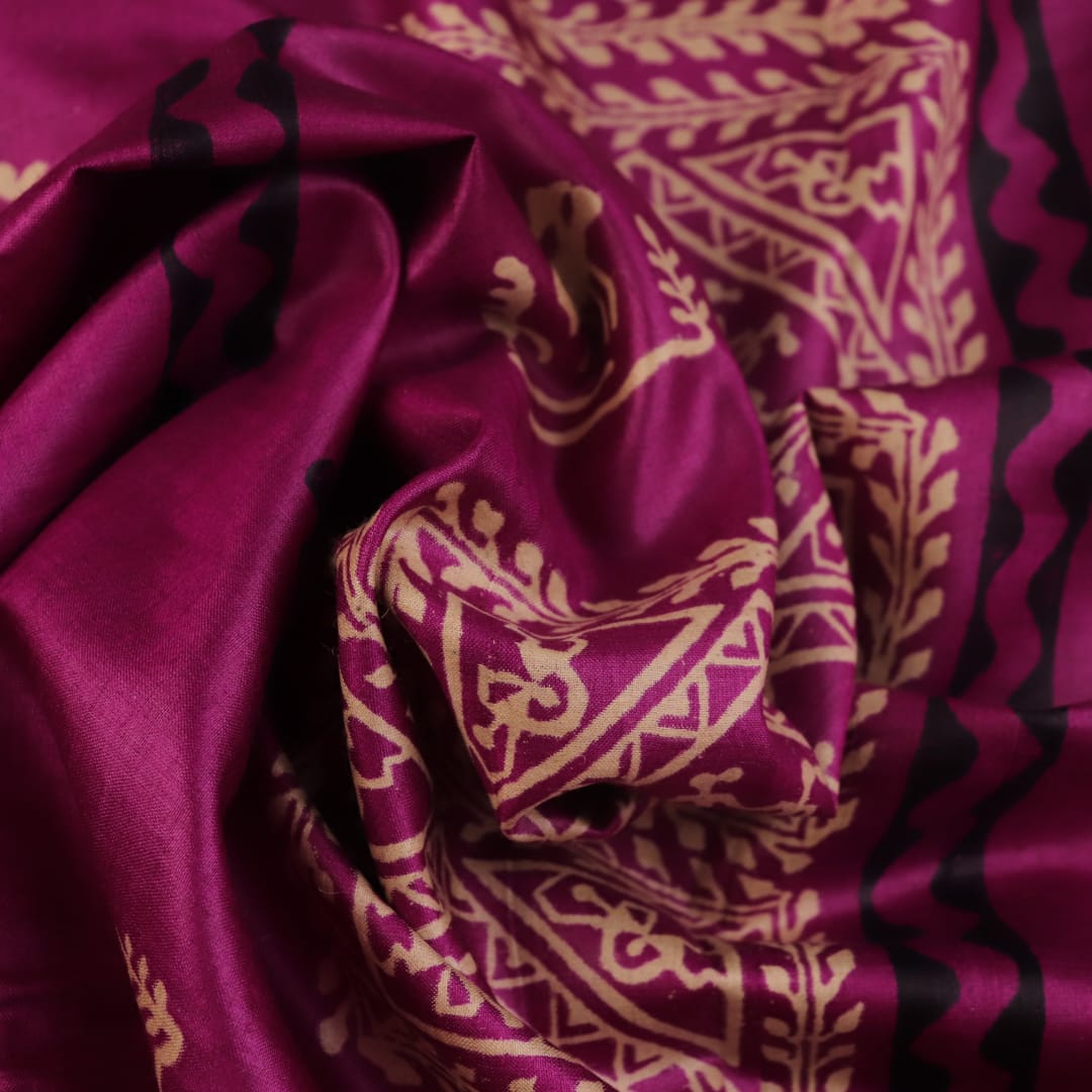 Close-up of magenta Tussar silk saree fabric, showing the printed pattern and natural slub texture.