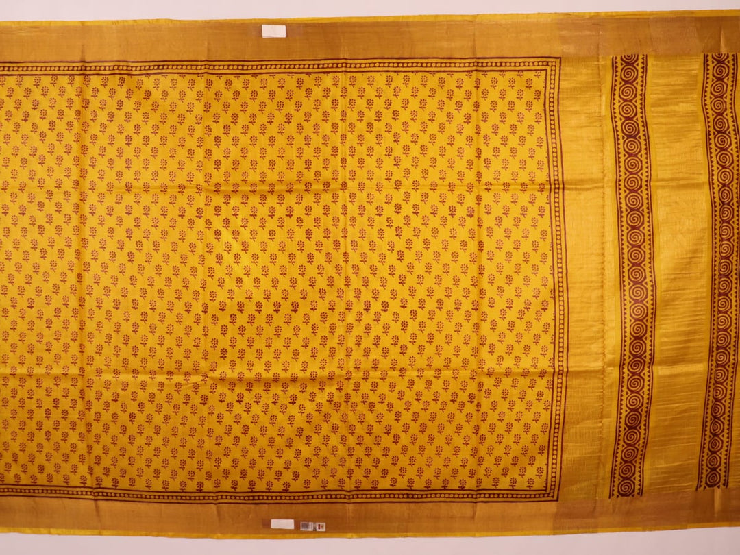 Close-up of the yellow printed Tussar silk saree's distinct slubby fabric texture.