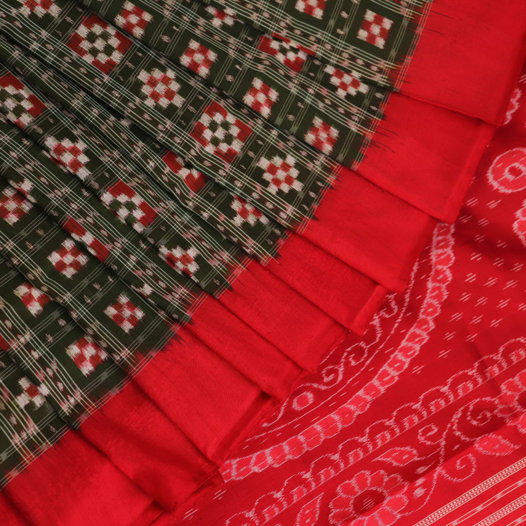 Close-up of green Sambalpuri silk saree fabric showing intricate woven motif texture and red thread details.