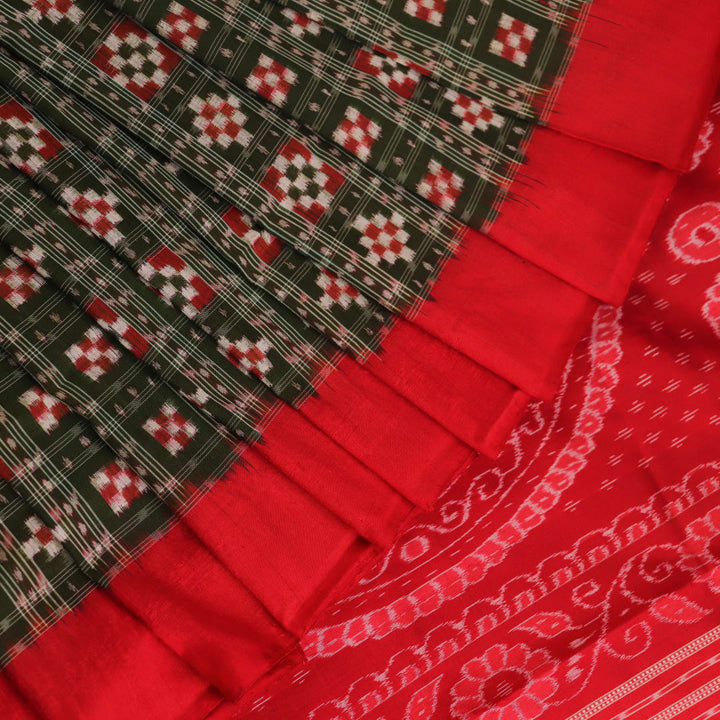 Close-up of green Sambalpuri silk saree fabric showing intricate woven motif texture and red thread details.