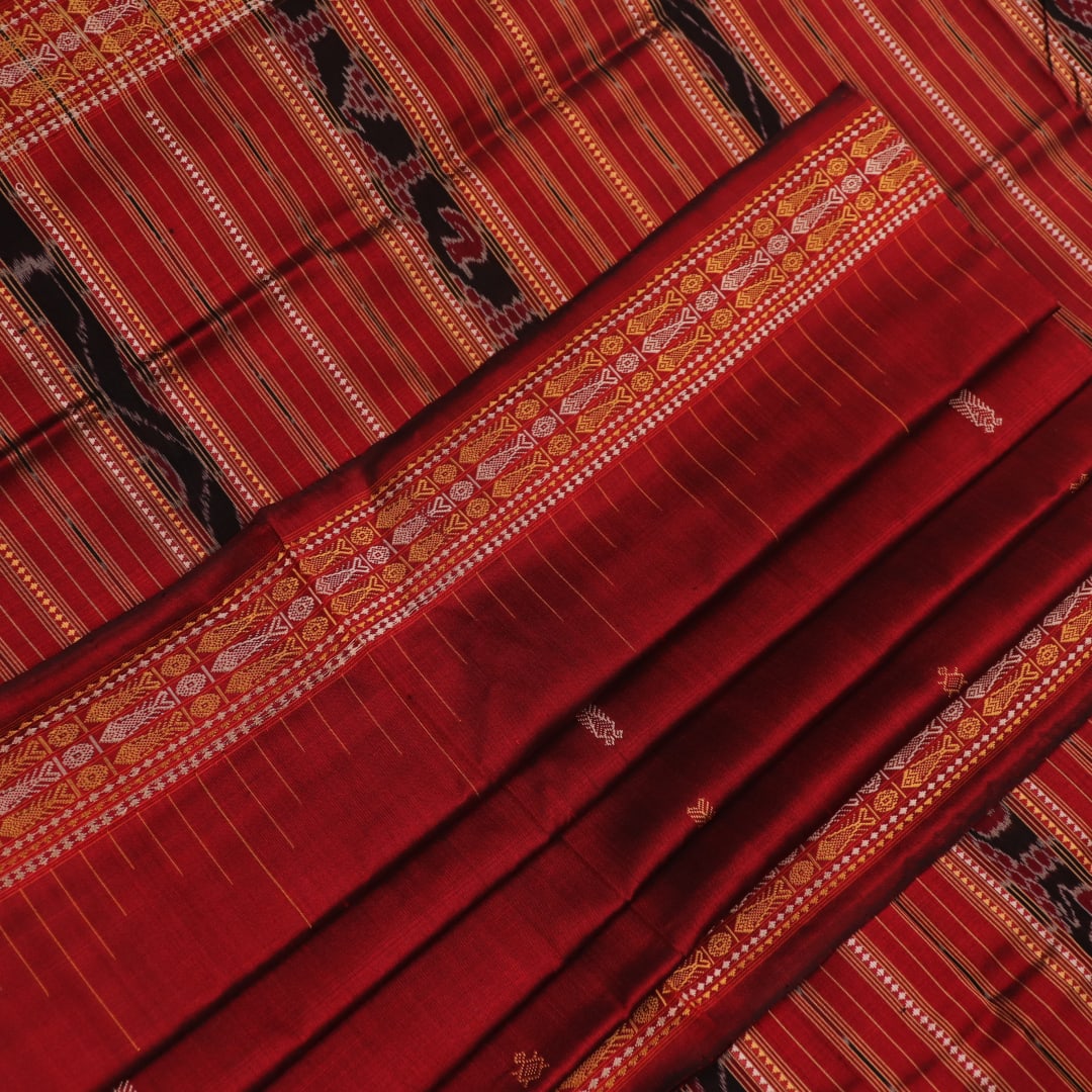 Close-up of maroon Sambalpuri Silk Saree fabric, showing intricate butta weave texture.