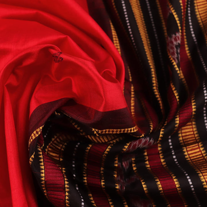 Textured close-up of red and black Sambalpuri Silk Saree fabric, highlighting the woven butta pattern.