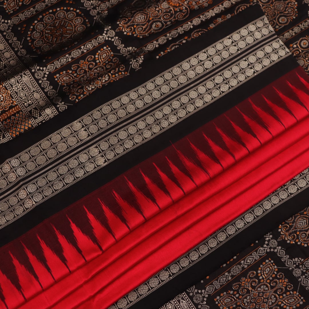 Detailed close-up of the red and black Bomkai silk saree fabric texture, featuring a butta pattern.
