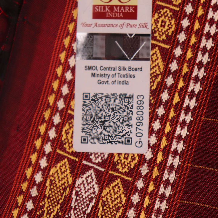 Close-up of maroon Sambalpuri Silk Saree fabric, showing intricate butta weave texture.