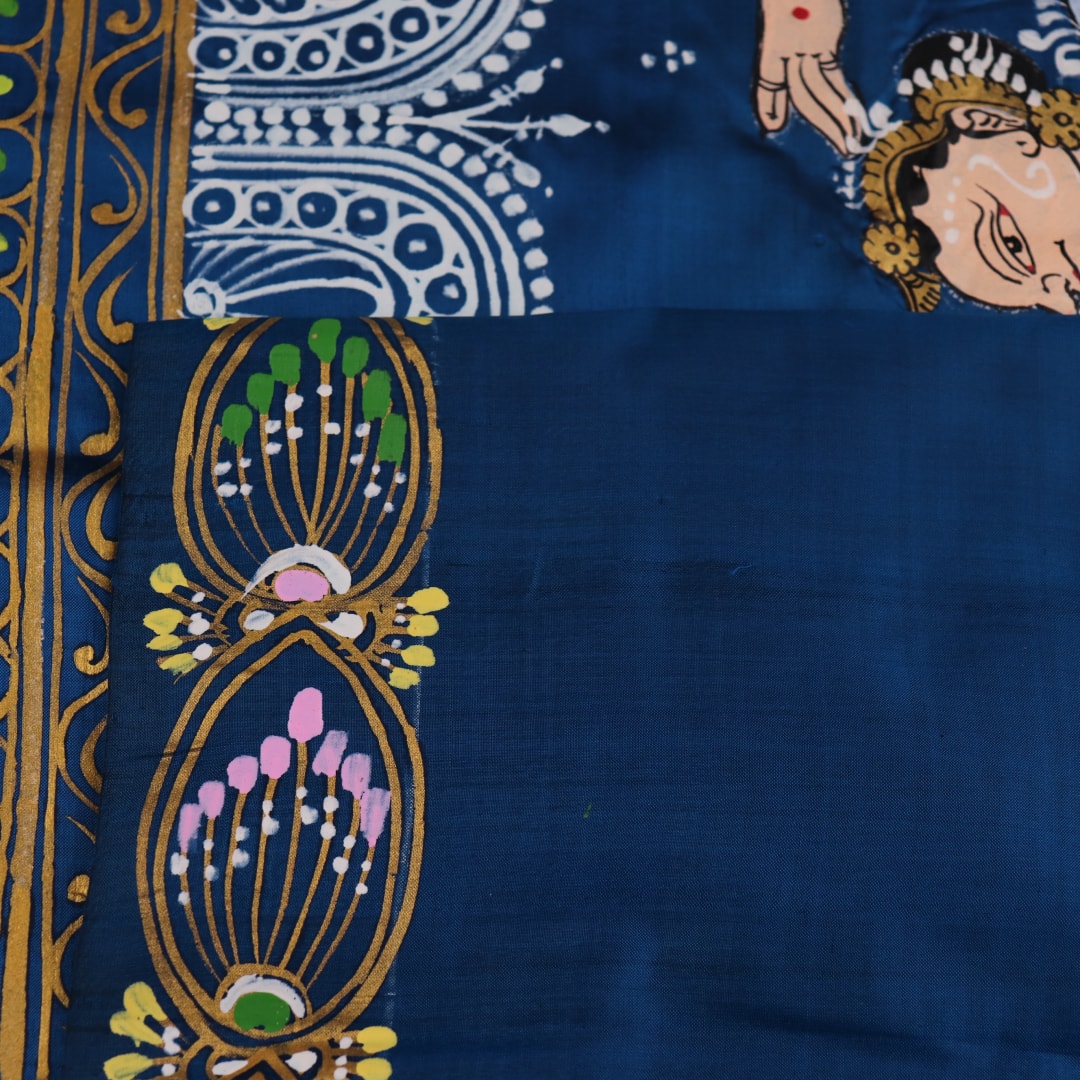 Close-up of handloom blue silk Patachitra saree fabric, showcasing the fine texture and hand-painted details.
