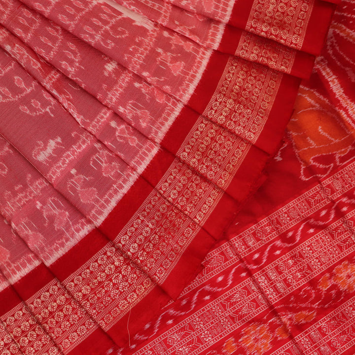 Close-up of a peach and red Sambalpuri silk saree fabric showing the intricate handloom texture and motifs.