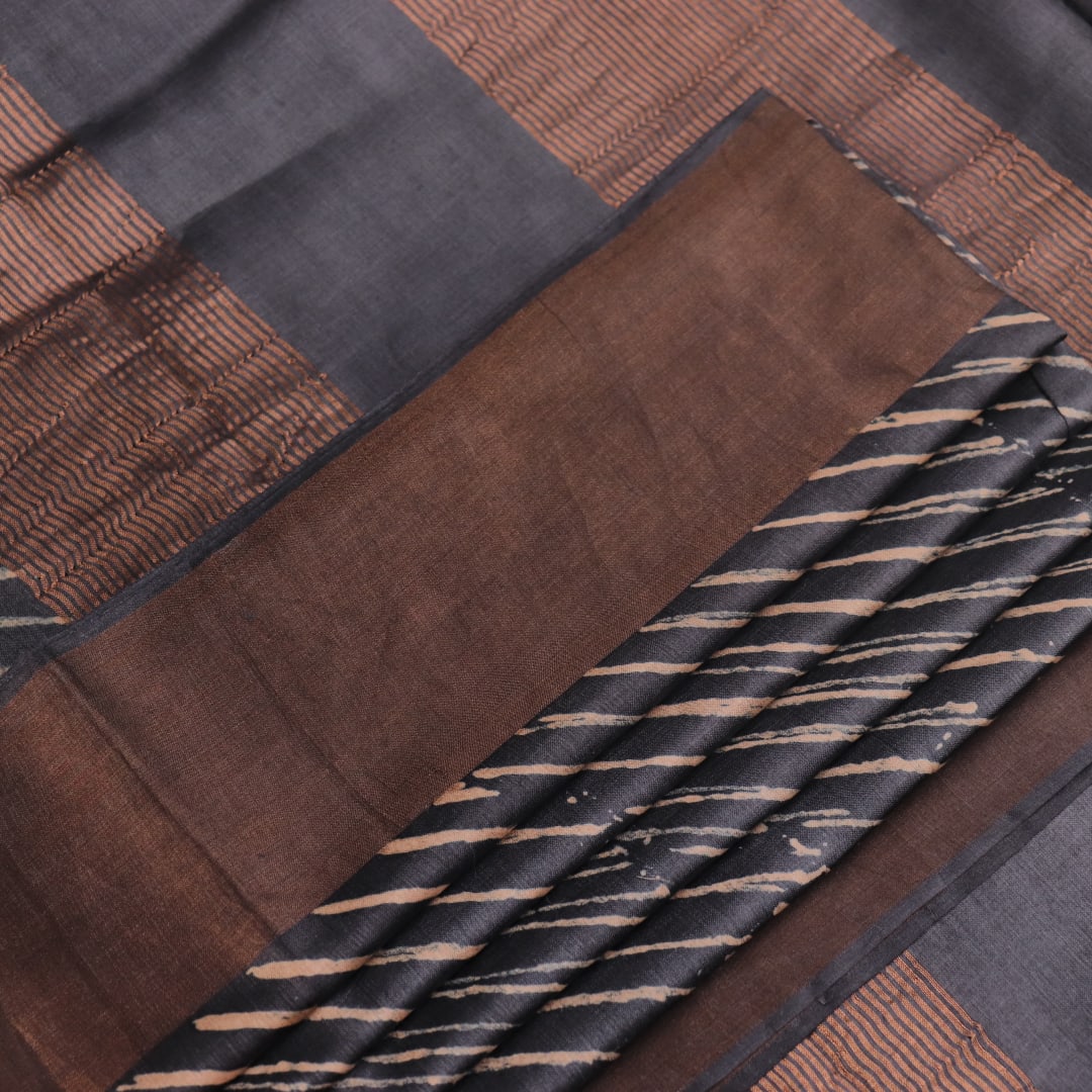 Close-up of the natural slub texture of grey printed Tussar silk saree fabric.