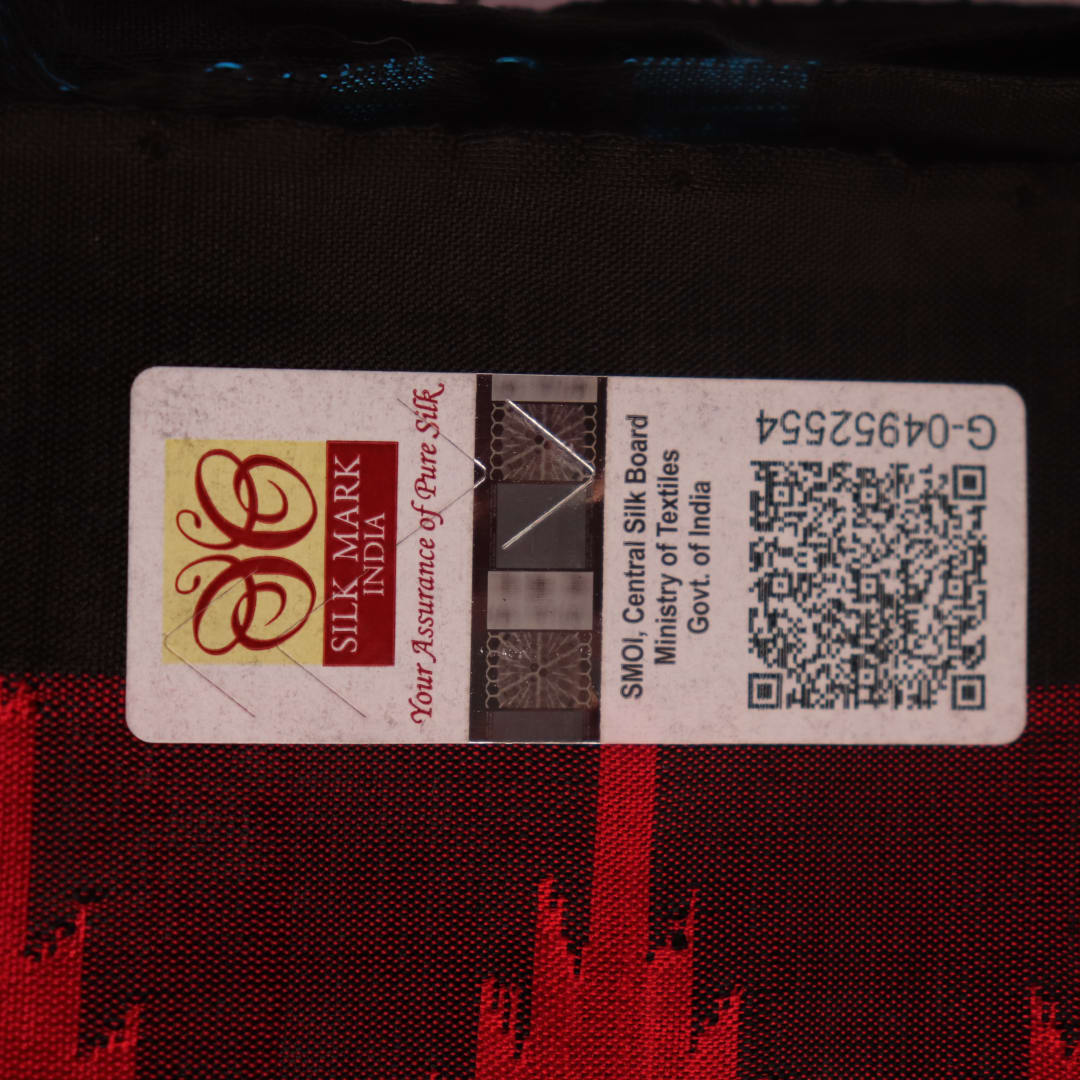Textured close-up of red and black Sambalpuri Silk Saree fabric, highlighting the woven butta pattern.