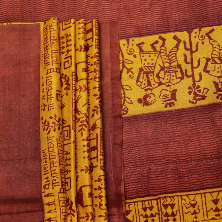 Close-up showing the textured weave of a yellow and brown printed Tussar silk saree.