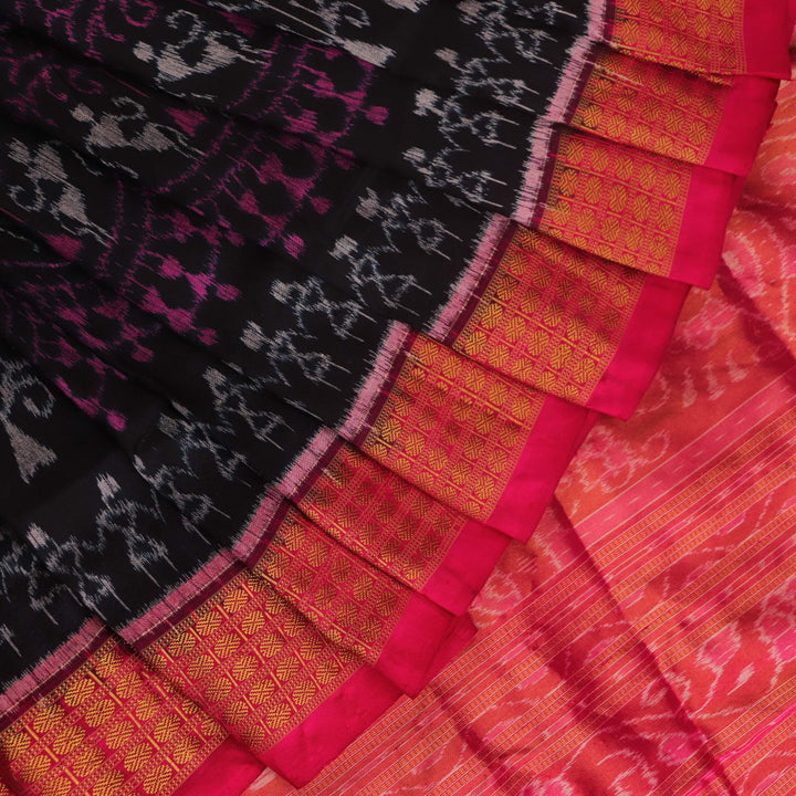 Close-up of black Sambalpuri silk saree fabric texture with subtle motifs and magenta threads.