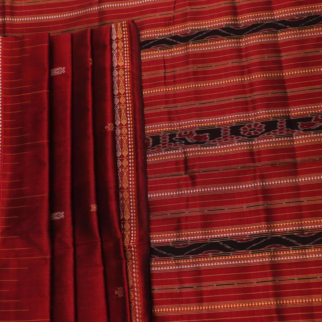 Close-up of maroon Sambalpuri Silk Saree fabric, showing intricate butta weave texture.