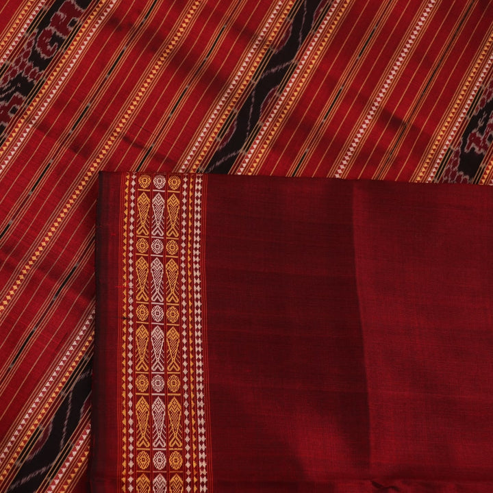 Close-up of maroon Sambalpuri Silk Saree fabric, showing intricate butta weave texture.