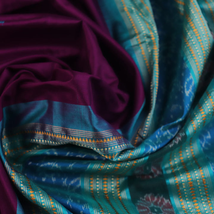 Close-up of the textured weave of a purple Sambalpuri silk saree with green accents and butta pattern.