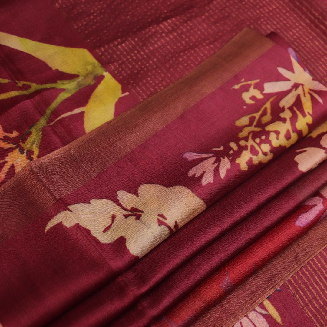 Close-up of maroon Tussar silk saree fabric, emphasizing its distinct texture and printed pattern.