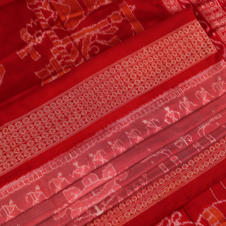 Close-up of a peach and red Sambalpuri silk saree fabric showing the intricate handloom texture and motifs.