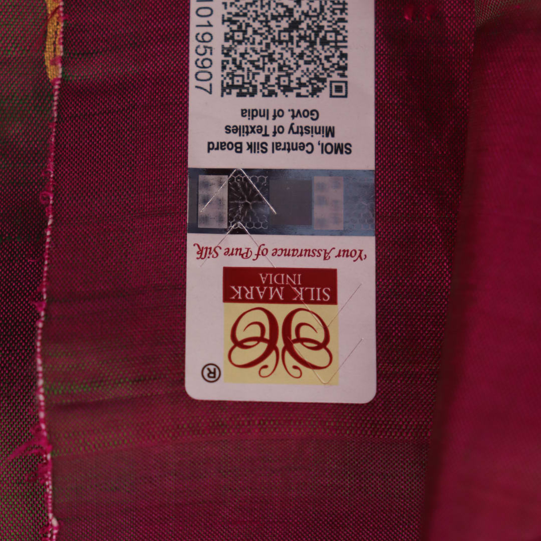 Close-up of magenta Patachitra silk saree fabric texture showing handloom weave and paint details.