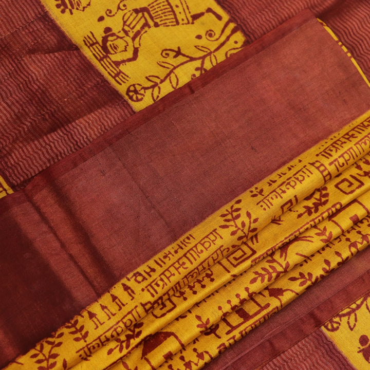 Close-up showing the textured weave of a yellow and brown printed Tussar silk saree.