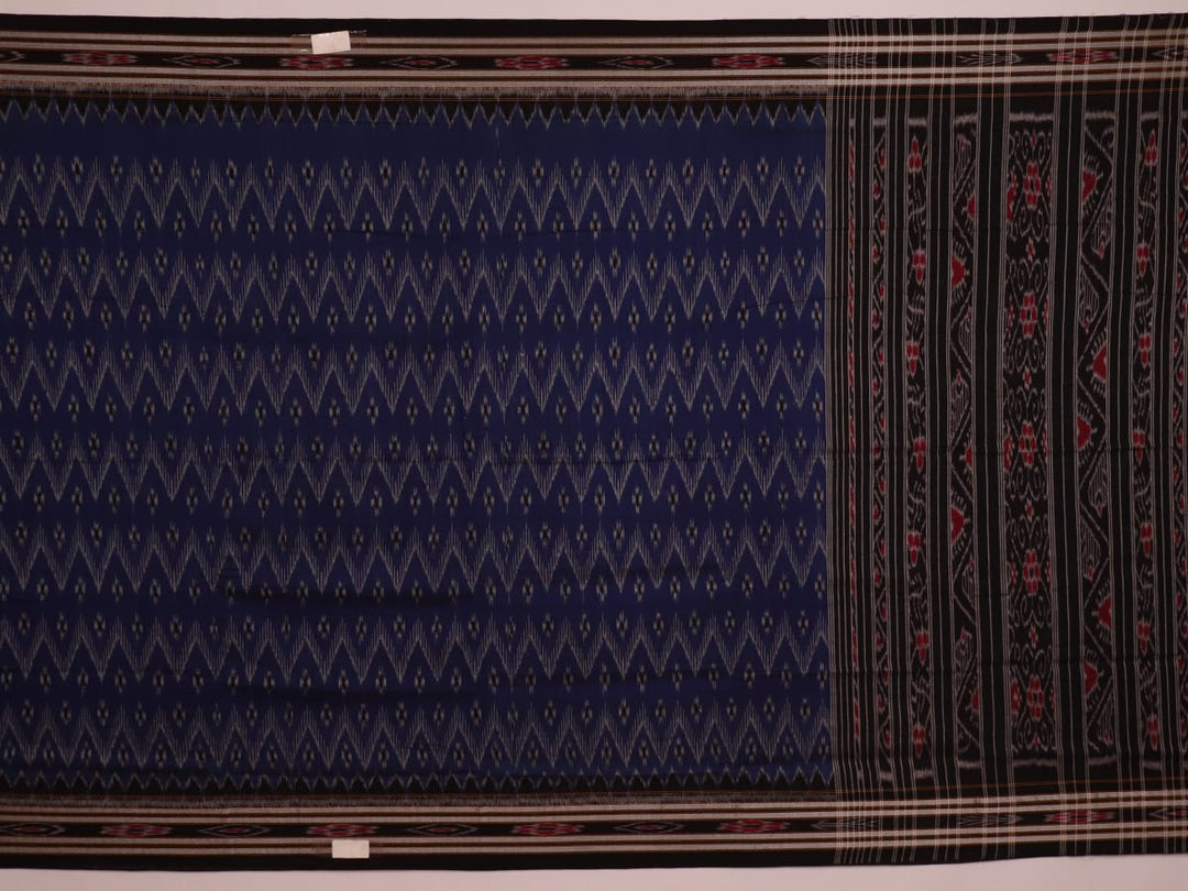 A person wearing a vibrant blue cotton Sambalpuri saree with black motifs, styled in a traditional drape.