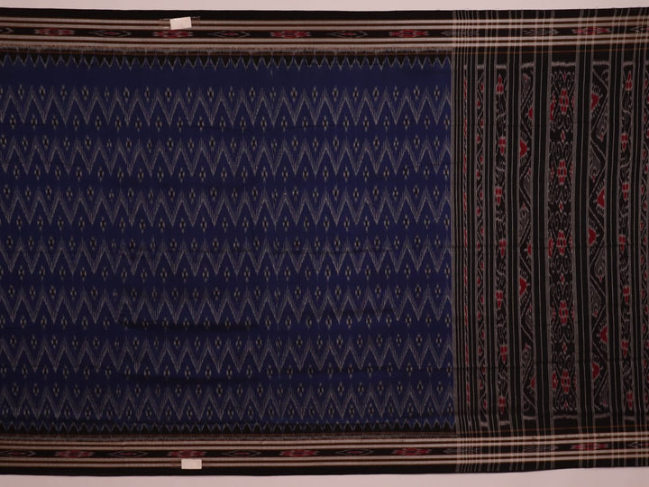 A person wearing a vibrant blue cotton Sambalpuri saree with black motifs, styled in a traditional drape.
