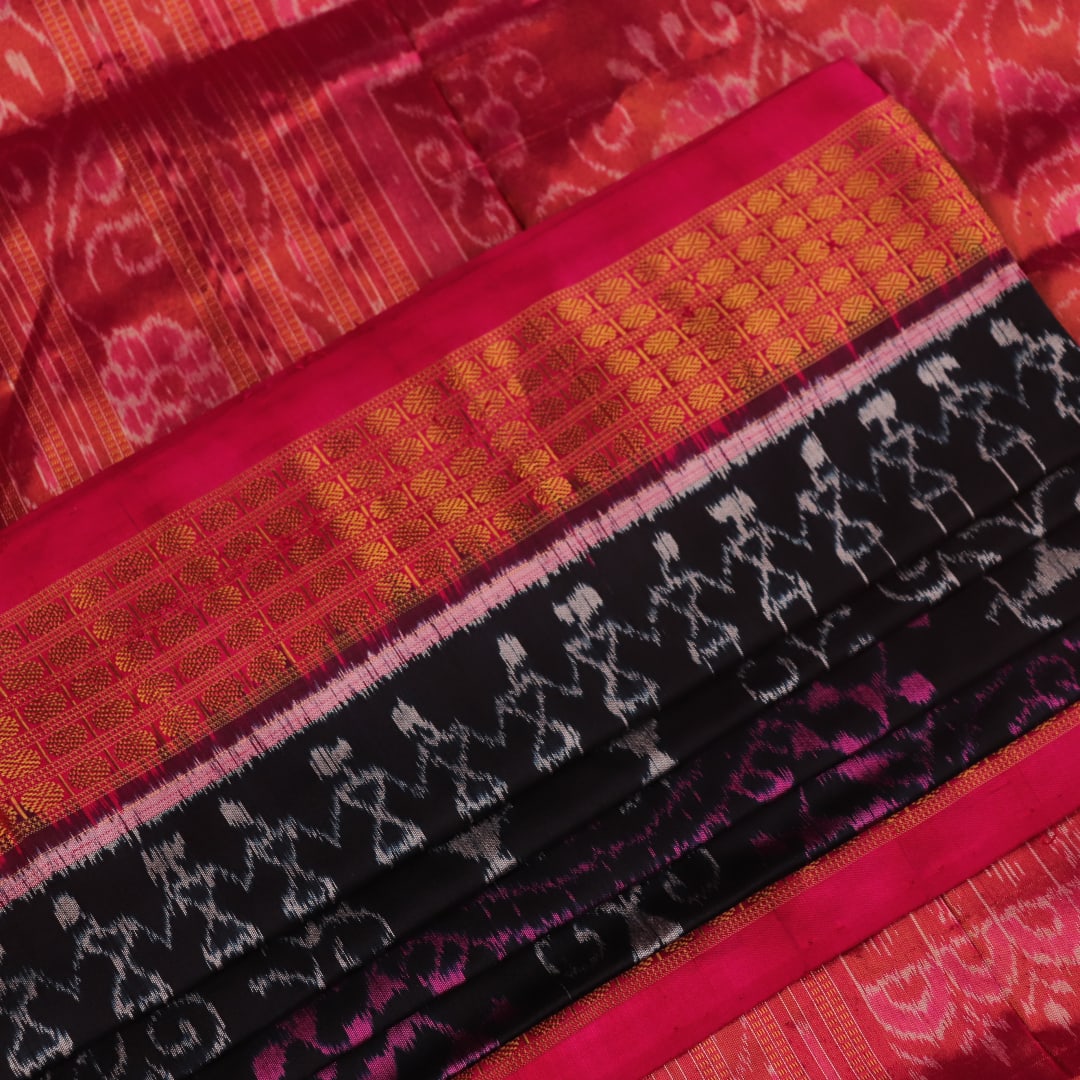 Close-up of black Sambalpuri silk saree fabric texture with subtle motifs and magenta threads.
