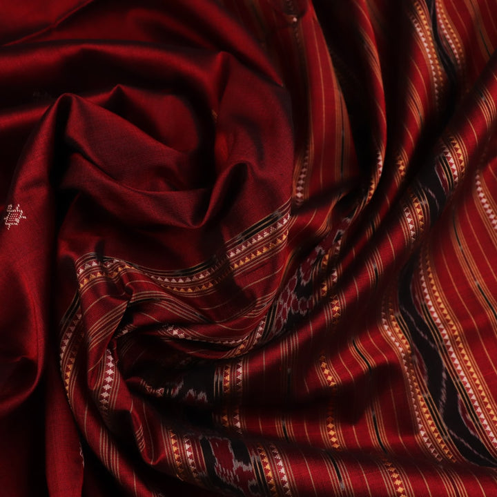 Close-up of maroon Sambalpuri Silk Saree fabric, showing intricate butta weave texture.
