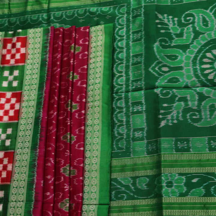 Close-up of magenta Sambalpuri silk saree fabric texture, showcasing intricate handloom weave and subtle motifs.