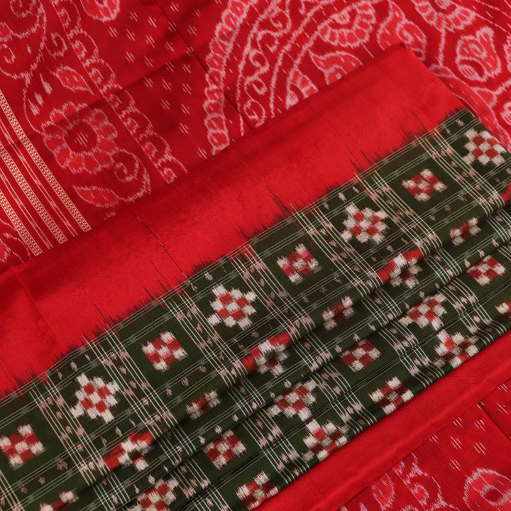 Close-up of green Sambalpuri silk saree fabric showing intricate woven motif texture and red thread details.