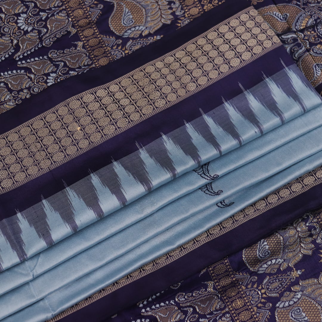 Close-up fabric texture of a blue Bomkai silk saree, revealing intricate butta pattern weave.