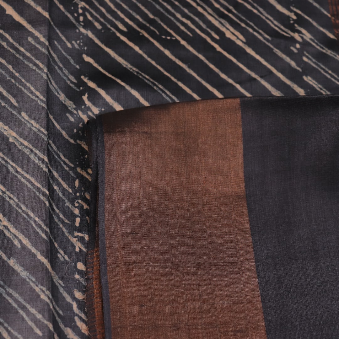 Close-up of the natural slub texture of grey printed Tussar silk saree fabric.