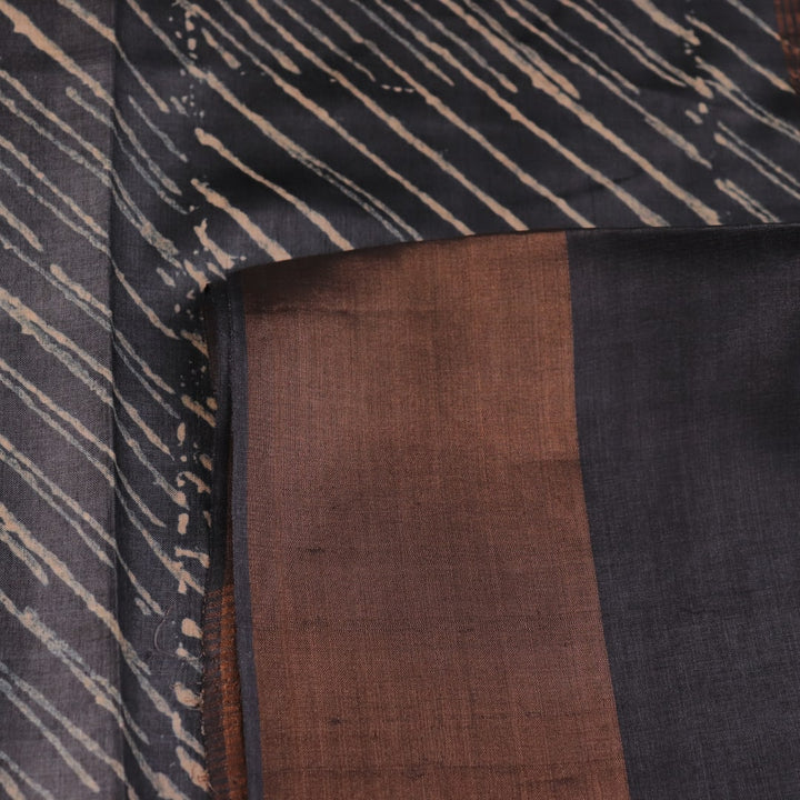 Close-up of the natural slub texture of grey printed Tussar silk saree fabric.