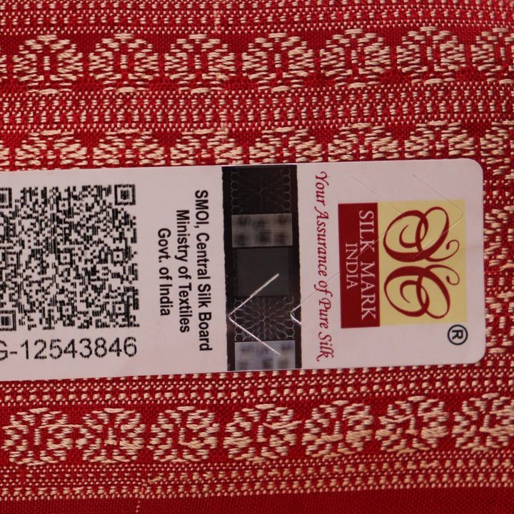 Close-up of a peach and red Sambalpuri silk saree fabric showing the intricate handloom texture and motifs.