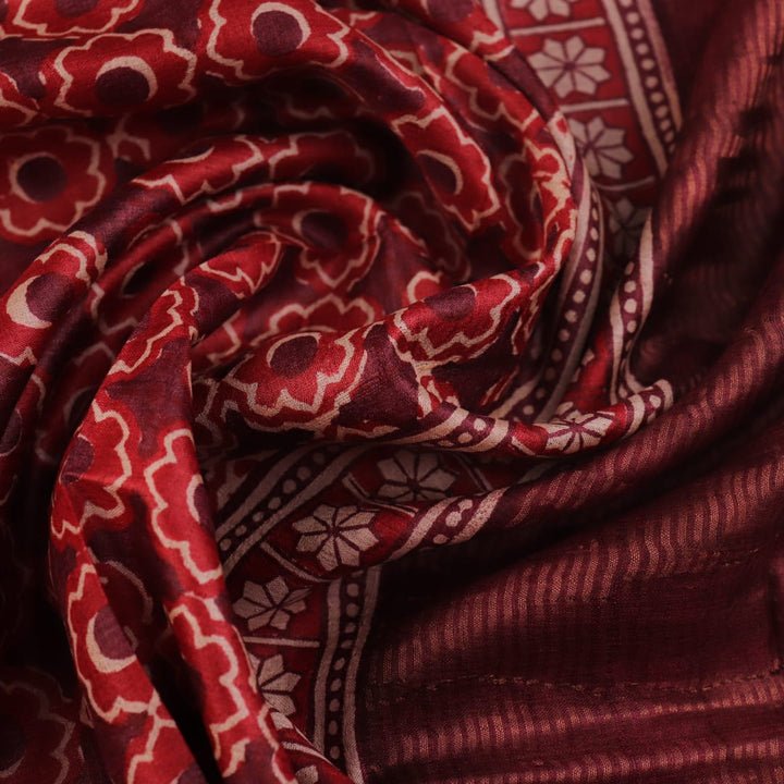 Close-up of maroon Tussar silk saree fabric, revealing its characteristic slub texture and printed details.