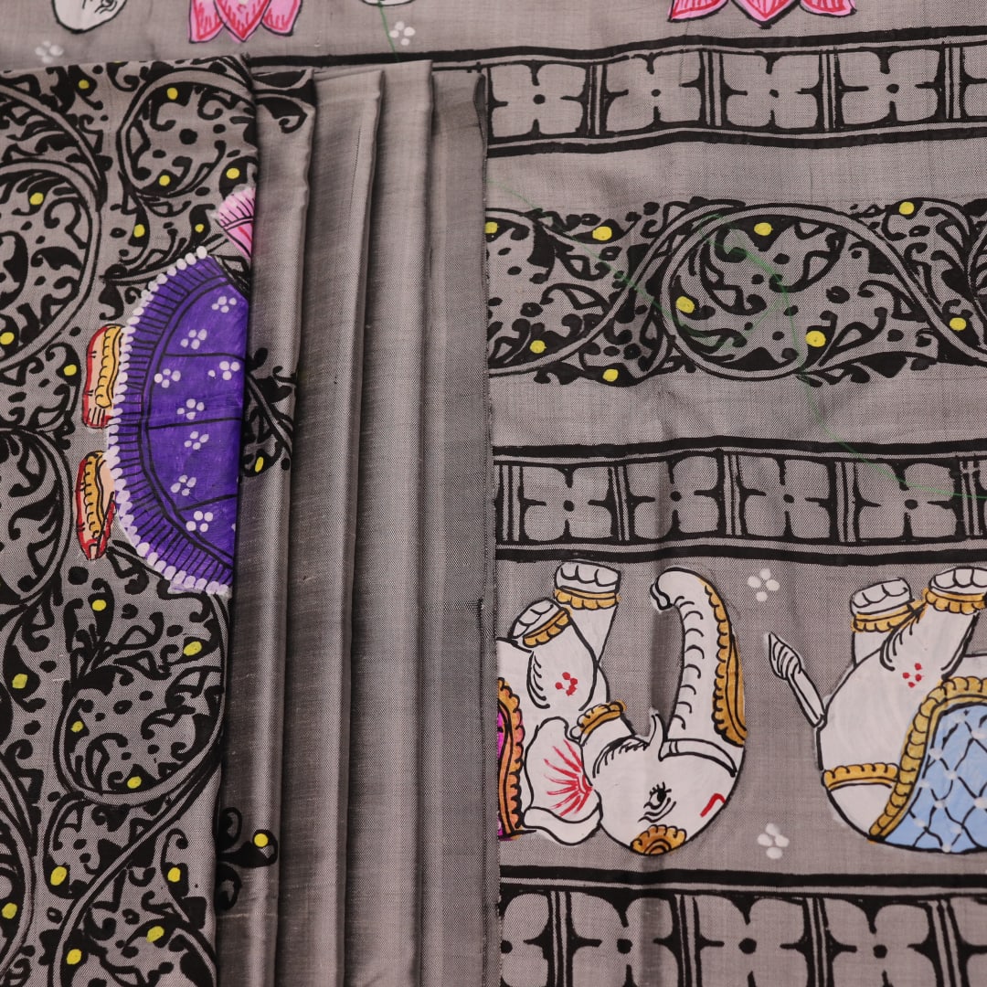 Close-up of grey silk Patachitra saree fabric showing hand-painted texture and intricate weave detail.
