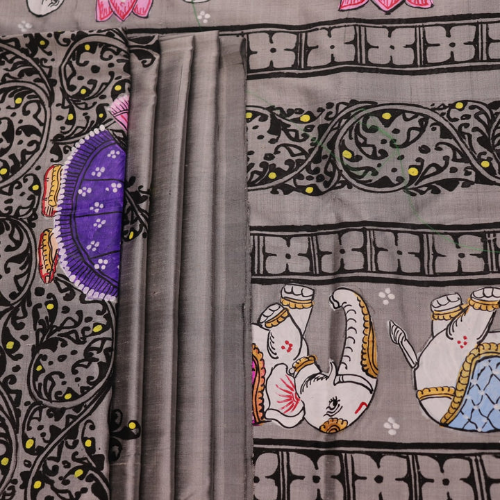 Close-up of grey silk Patachitra saree fabric showing hand-painted texture and intricate weave detail.