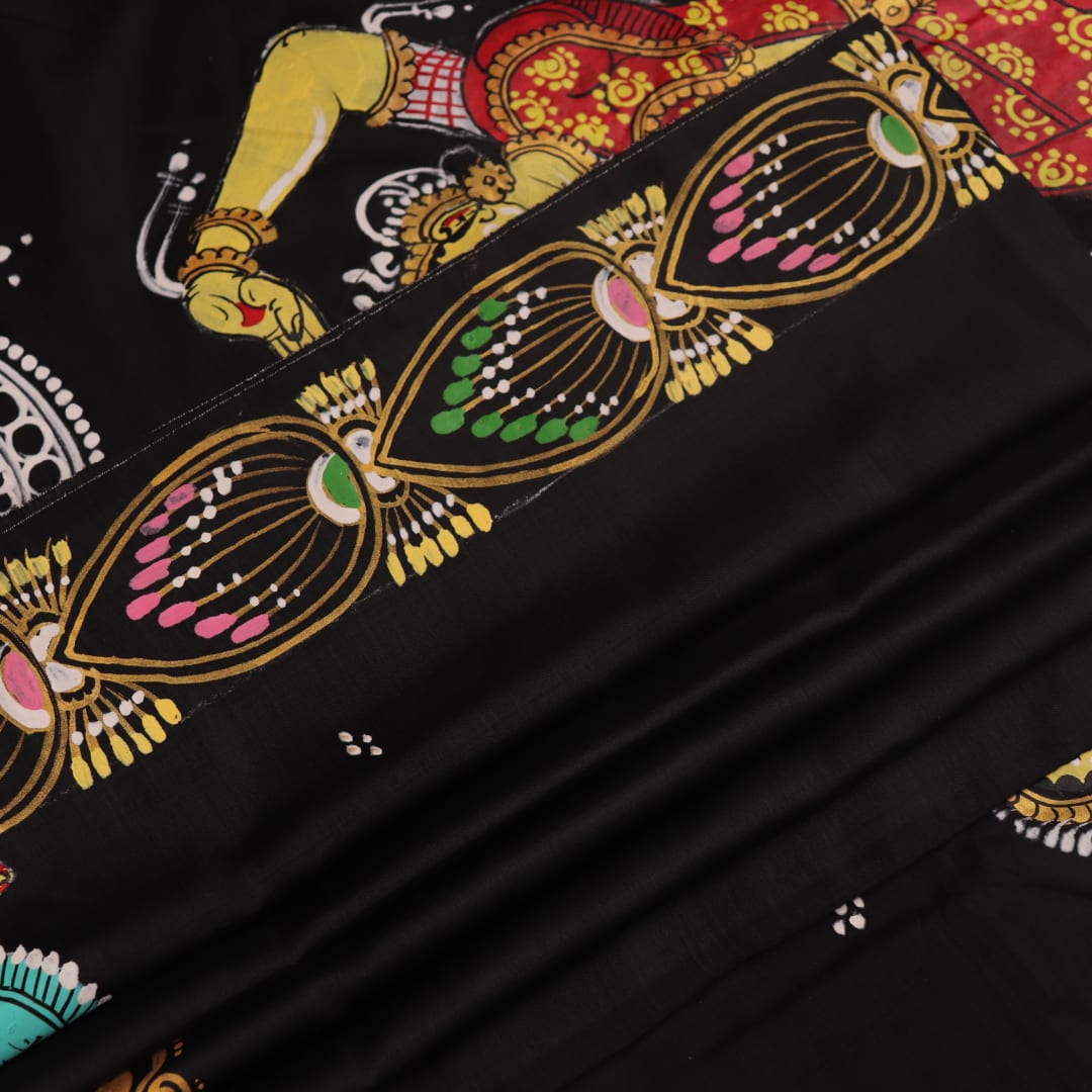 Close-up of black silk Patachitra saree fabric texture showing hand-painted details.