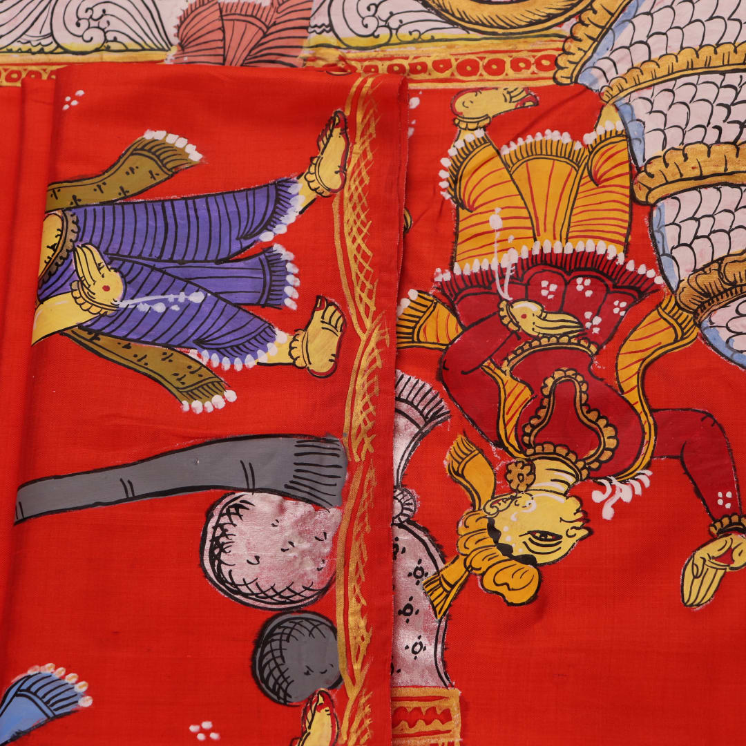 Close-up of red Patachitra silk saree fabric showing hand-painted texture.
