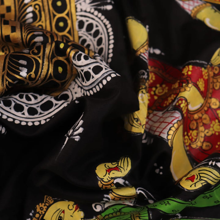 Close-up of black silk Patachitra saree fabric texture showing hand-painted details.